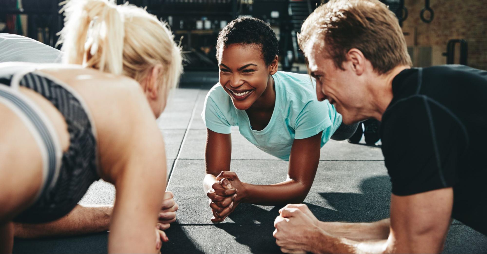 5 Ways Exercise Boosts Your Self-Esteem 2 Smiling friends planking together during a gym workout class